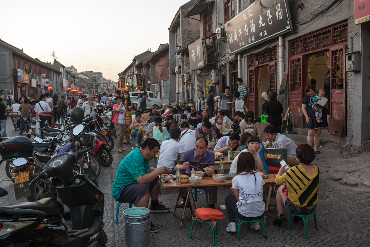 Eine Straße in Luoyang ist voll mit Tischen und kleinen Stühlen, an denen Kundschaft zu Abend isst. Luoyang - Henan - China