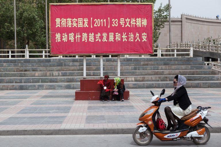 An vielen Orten befinden sich verschiedenste Plakate und Aufrufe. Das Plakat an einer Straße in Kashgar, im Süden der Provinz Xinjiang, ruft dazu auf: "Den Geist vom Guofa, Staatratsdokument, (2011) Nr. 33 umsetzen und Kashis sprunghafte Entwicklung und dauerhaften Frieden fördern“. Kashgar - Xinjiang - China