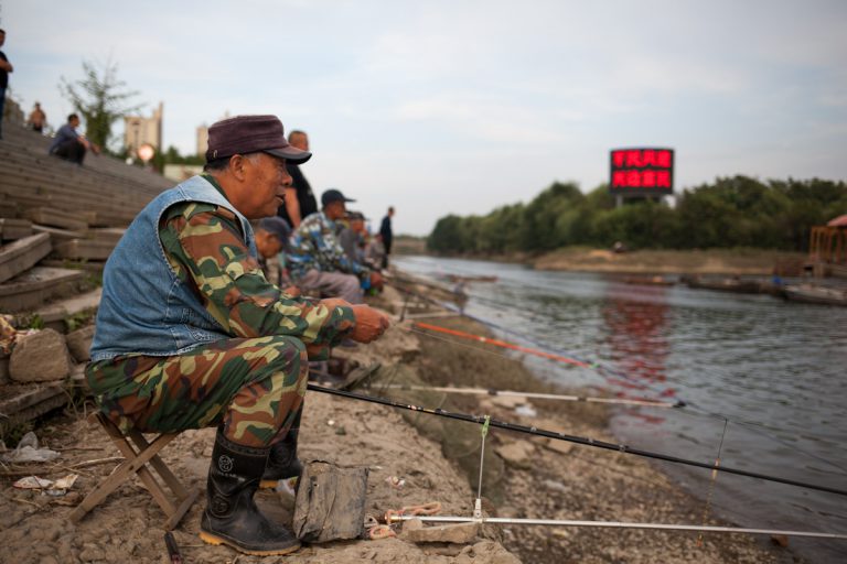 Mehrere Männer sitzen zum angeln am Fluss Yalu in der Nähe von Dandong. Dandong ist eine Grenzstadt zu Nordkorea, gegenüber von Sinuiju. Dandong - Liaoning - China