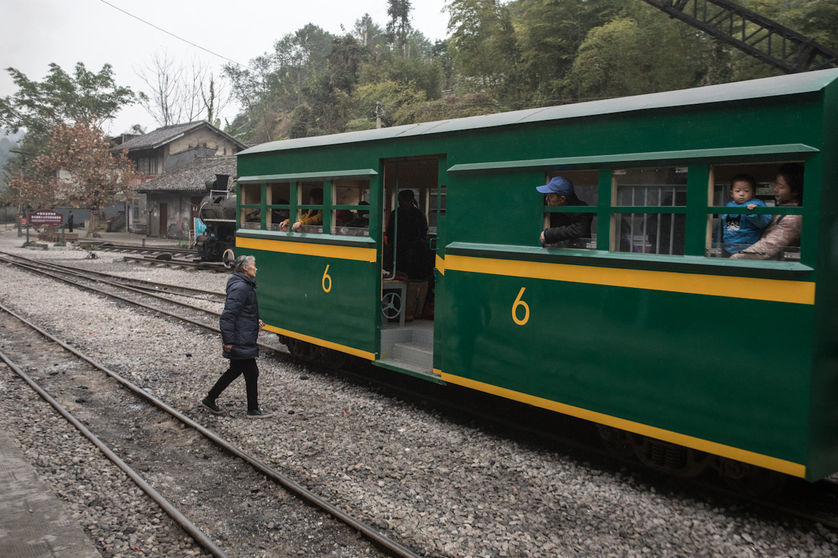 Eine Anwohnerin steigt in Mifengyan in den Zug nach Bagou. Der Zug hält zwischen den Gleisen.