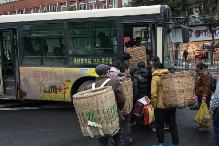 Lokale Anwohner fahren vom Wochenmarkt in Zigong, mit dem Bus zurück in das Dorf Aiye. Für den Transport tragen sie auf dem Rücken große Körbe aus Bambus. Zigong - Sichuan - China