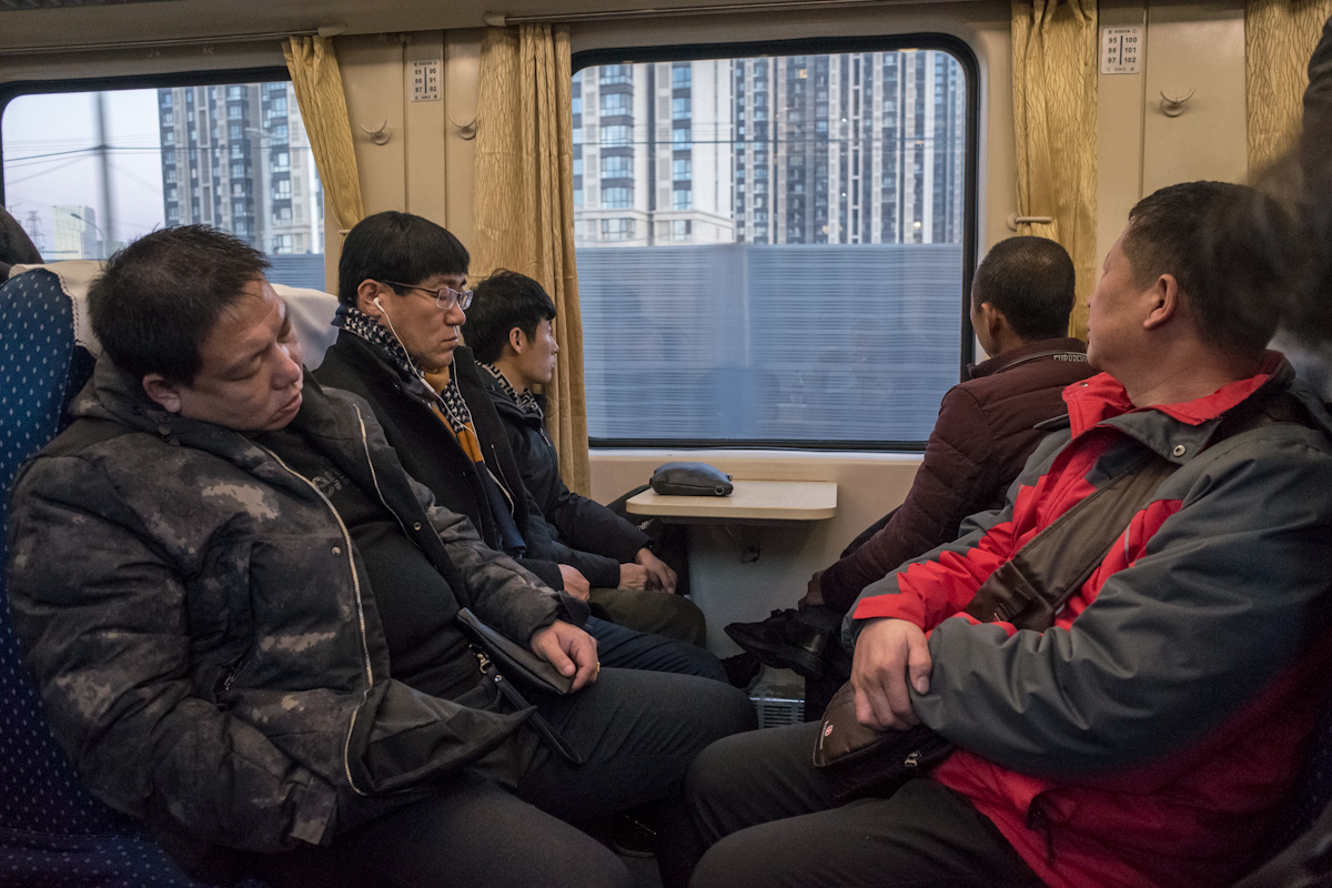 Passagiere schauen im morgendlichen Berufsverkehr in Peking aus dem Zug, auf eine neu errichtete Hochhaussiedlung. Peking - China