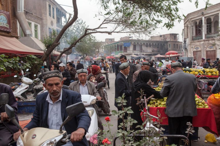 Mehrere Bewohner durchqueren mit ihrem Mofa einen Markt in der Altstadt in Kashgar. Der Markt wird von vielen Anwohnern für den täglichen Bedarf genutzt. Kashgar - Xinjiang - China