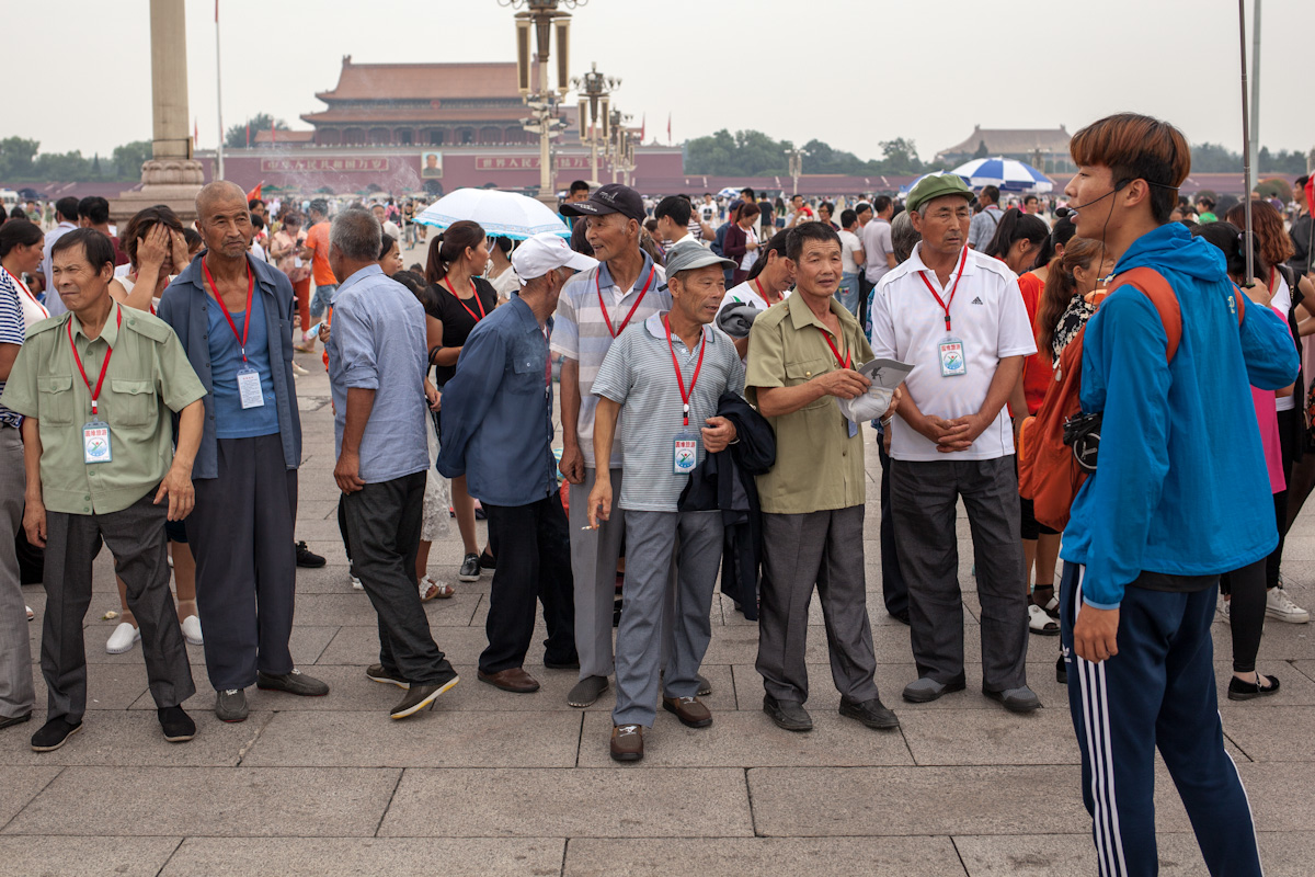 Ein Reiseführer spricht zu seiner Reisegruppe auf dem Platz des Himmlischen Friedens, die woanders hinschaut und kaum zuzuhören scheint. tiananmen platz square Peking - China