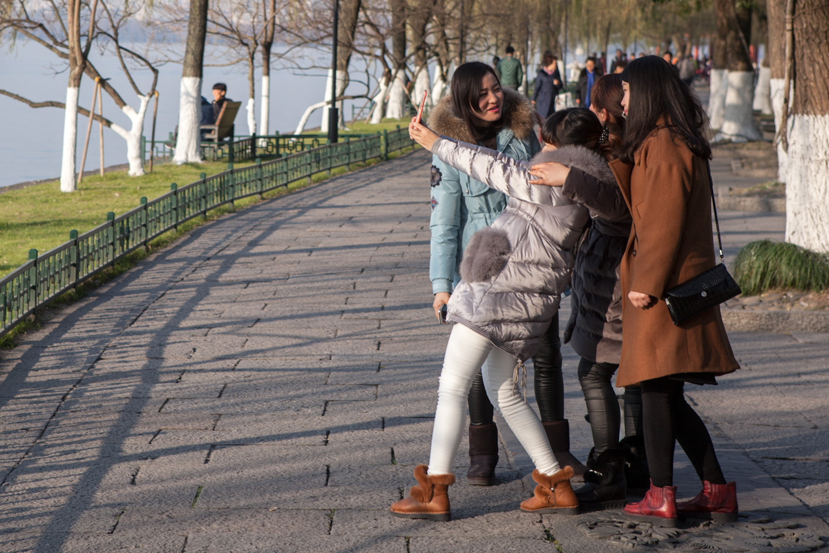 Mehrere junge Frauen fotografieren sich selbst im Park am Seeufer des West Lake. Hangzhou - Zhejiang - China