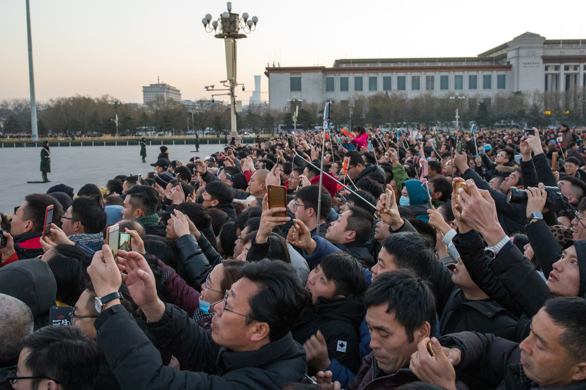 Besucher auf dem Platz des Himmlischen Friedens sehen sich die Zeremonie zum Hissen der Nationalflagge Chinas an. Peking - China