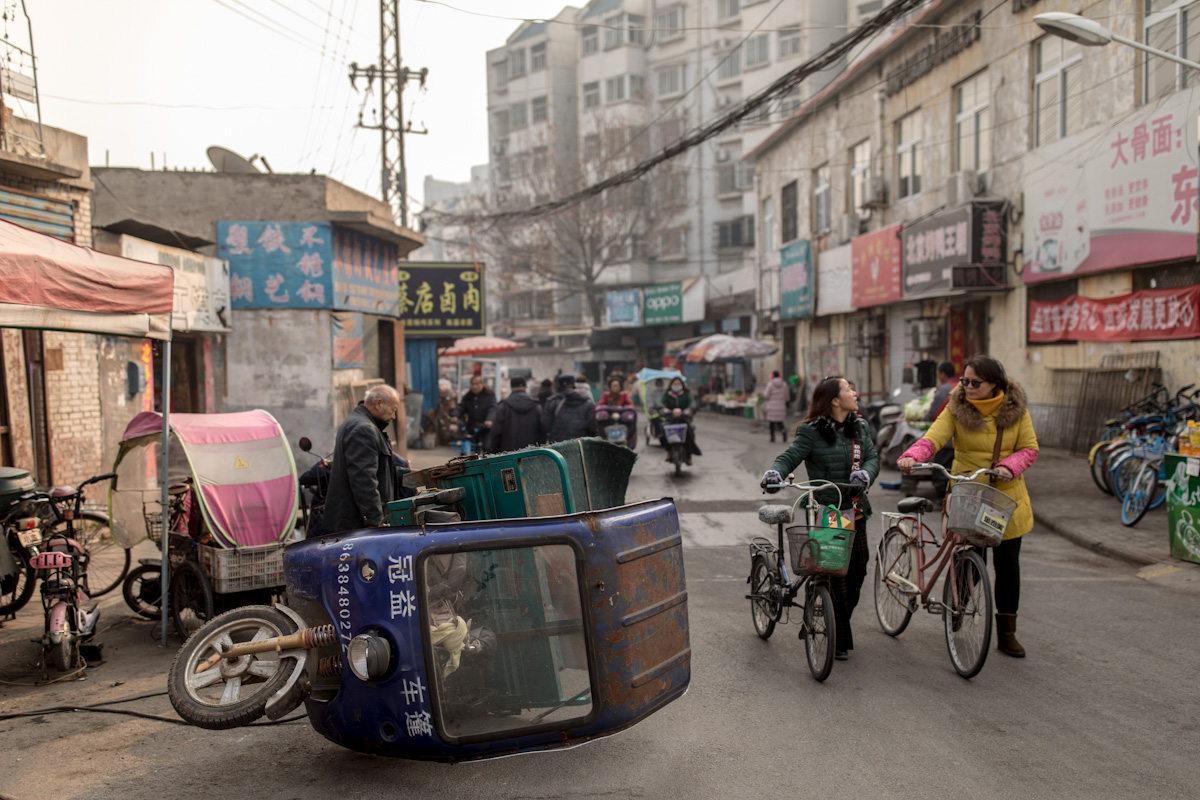 Auf einer Straße in einem Viertel in Luoyang repariert ein Mann sein motorisiertes Transportdreirad. Luoyang - Henan - China