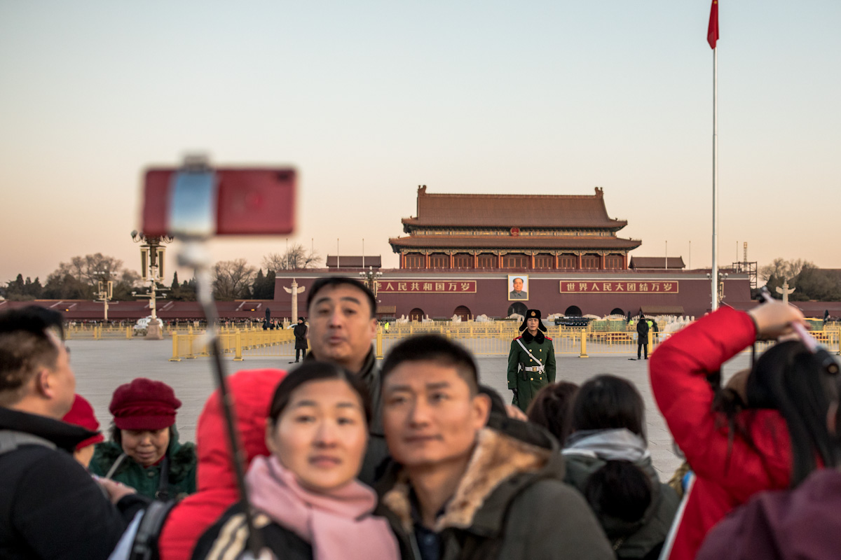 Eine Paar fotografiert sich nach der Zeremonie zum Hissen der Nationalflagge auf dem Platz des Himmlischen Friedens. Im Hintergrund befindet sich das Tor des Himmlischen Friedens. Peking - China