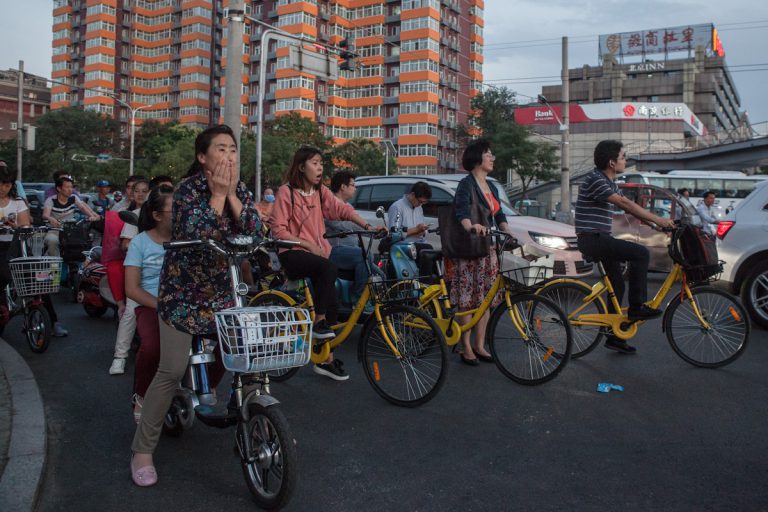 An einer Kreuzung warten Radfahrer auf ihrem abendlichen Weg, dass sie weiterfahren können.